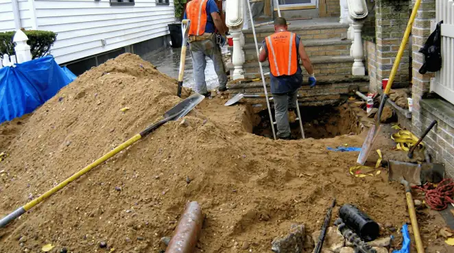 Contractors performing foundation protection and exterior drainage excavation near residential home steps in Cedar Rapids, IA
