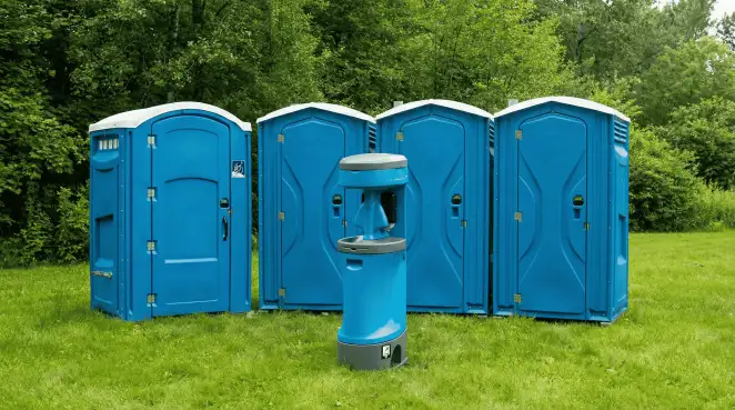 Four blue portable toilets and a matching hand washing station on grass near trees, a common sight at local outdoor events in Cedar Rapids, IA